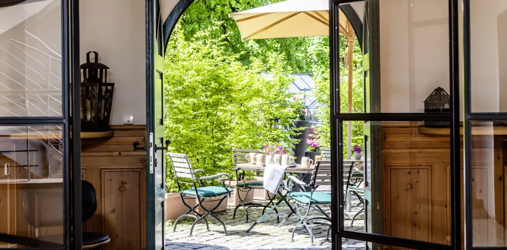 Blick von der Lobby  des Hotels Kloster Hornbach hinaus durch die geöffnete Tür zum Biergarten 