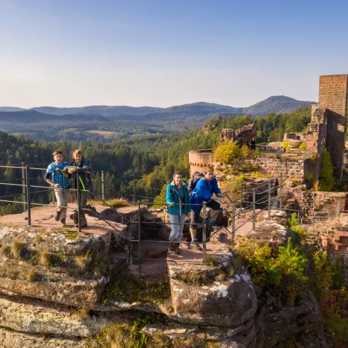 zwei Erwachsene und zwei Kinder stehen auf einer Pfälzer Burgruinie im Hintergrund der Pfälzerwald